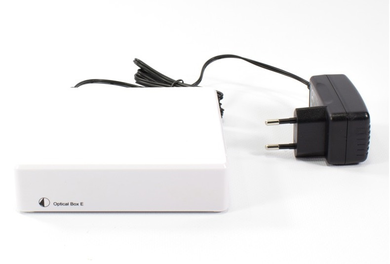 En vit RIAA-förstärkare med optisk utgång och strömadapter.