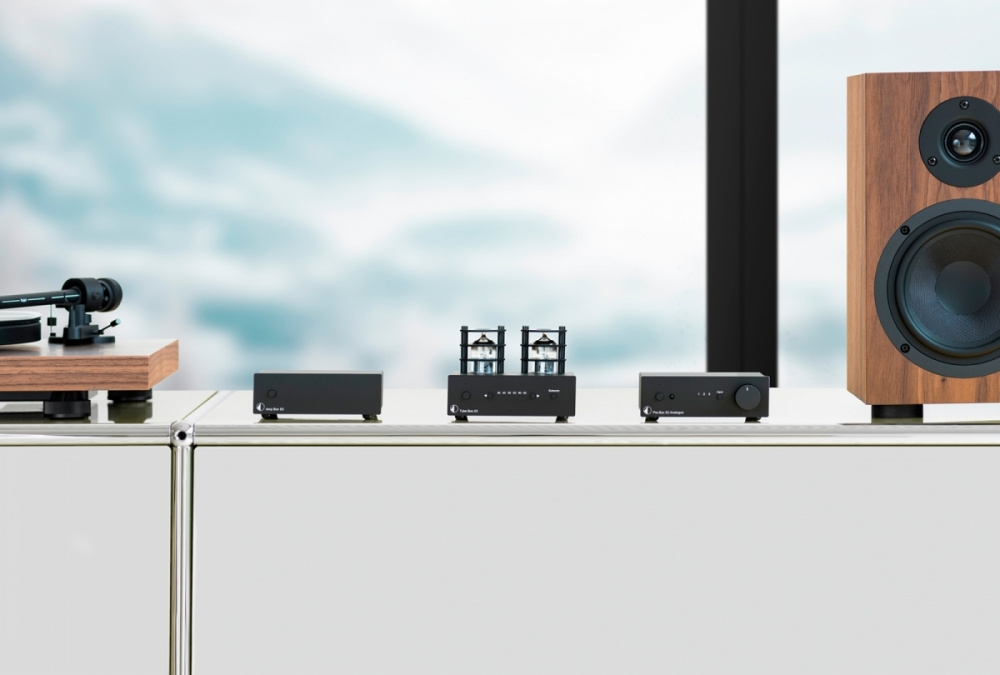 Bild av ljudutrustning med Pro-Ject Pre Box S2 Analogue och högtalare i trä.