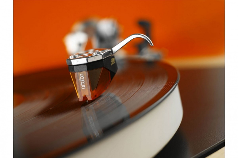En pickup som spelar vinylskivor, med orange bakgrund.