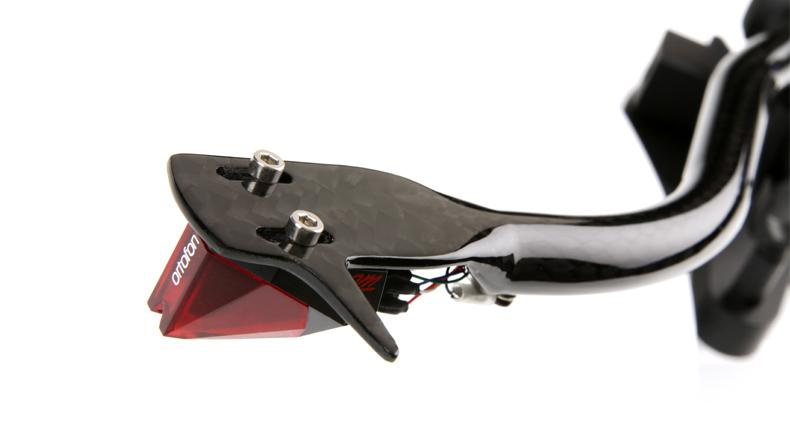 En del av en skivspelare med svart carbonfiber och röd nålspets.