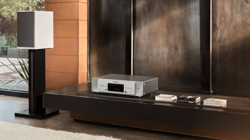 En svart Marantz CD60 CD-spelare på en mörk hylla med ljudsystem och cd-skivor.