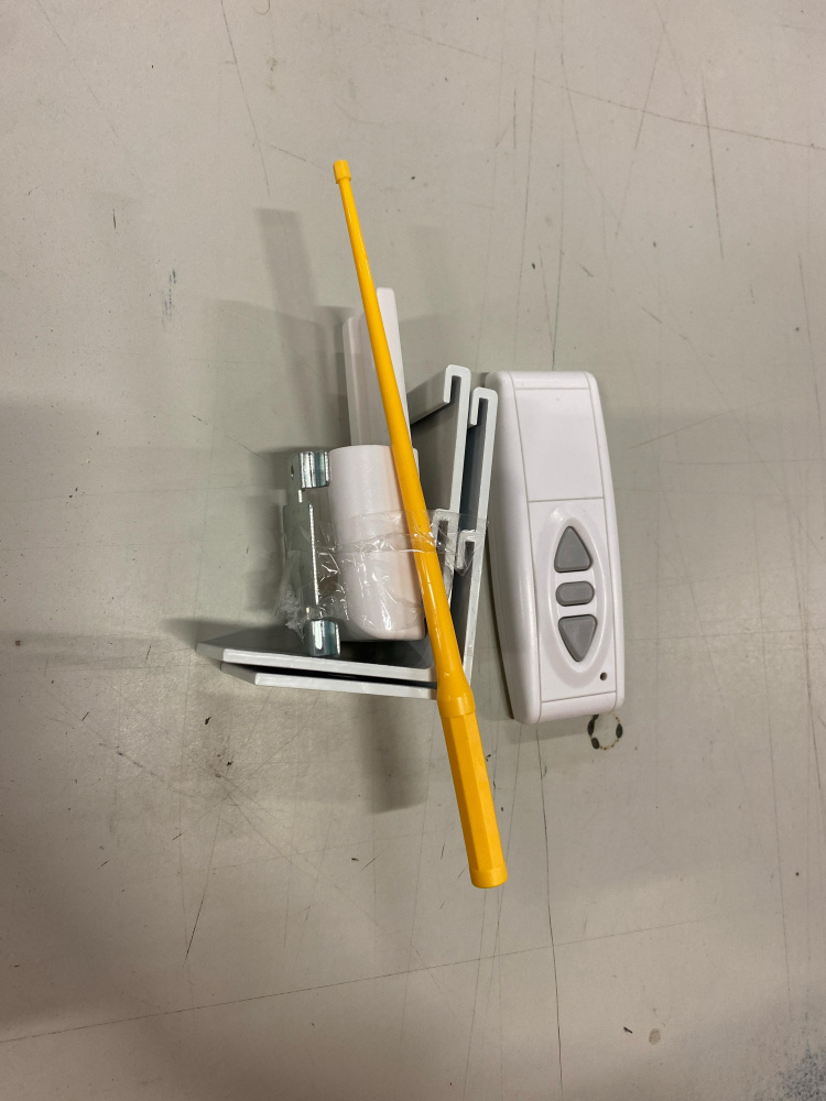 En uppsättning komponenter för motordriven duk, inklusive fjärrkontroll och olika fästen.