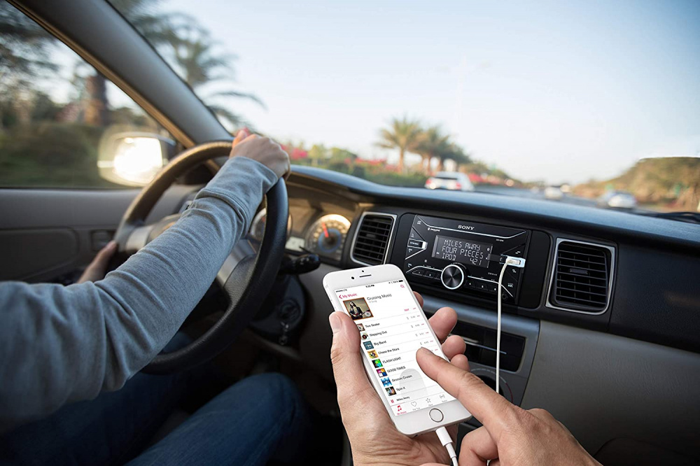 En bil med en förare som kontrollerar musik via telefon och Sony DSX-B700 stereo.