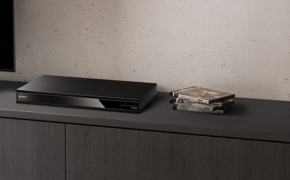 En svart Blu-ray spelare med några filmer på ett bord.