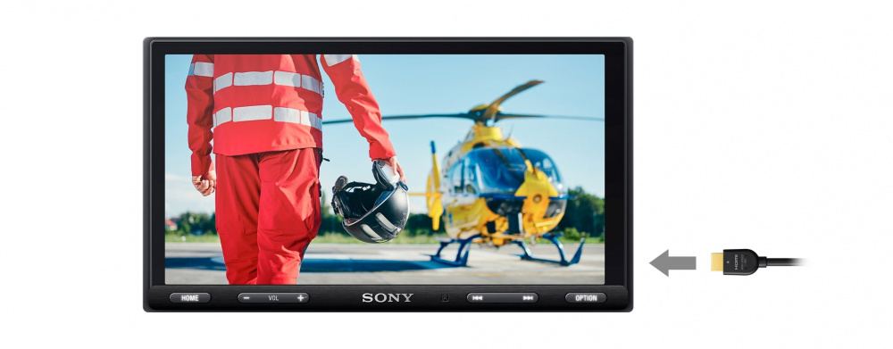 En bilstereo visar en pilot med hjälm och en helikopter i bakgrunden.