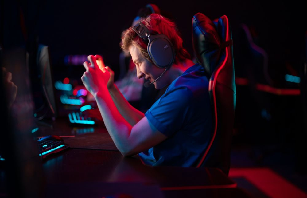 En spelare med hörlurar visar intensiva känslor vid datorn.