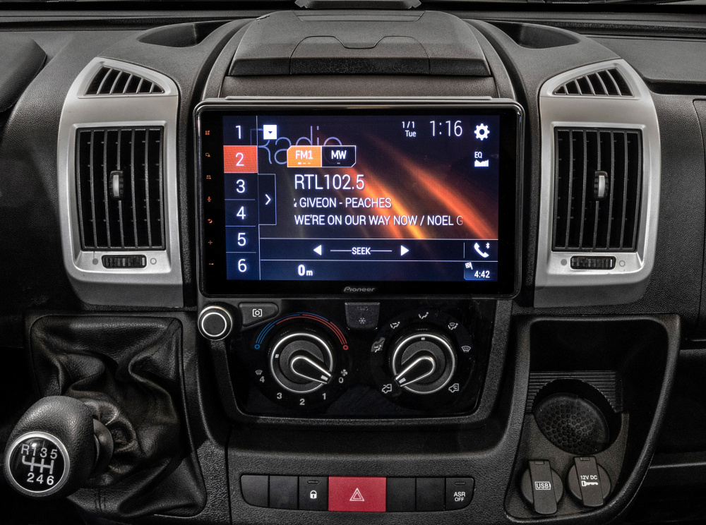 Bilstereo med skärm som visar radiostation och låtinformation.