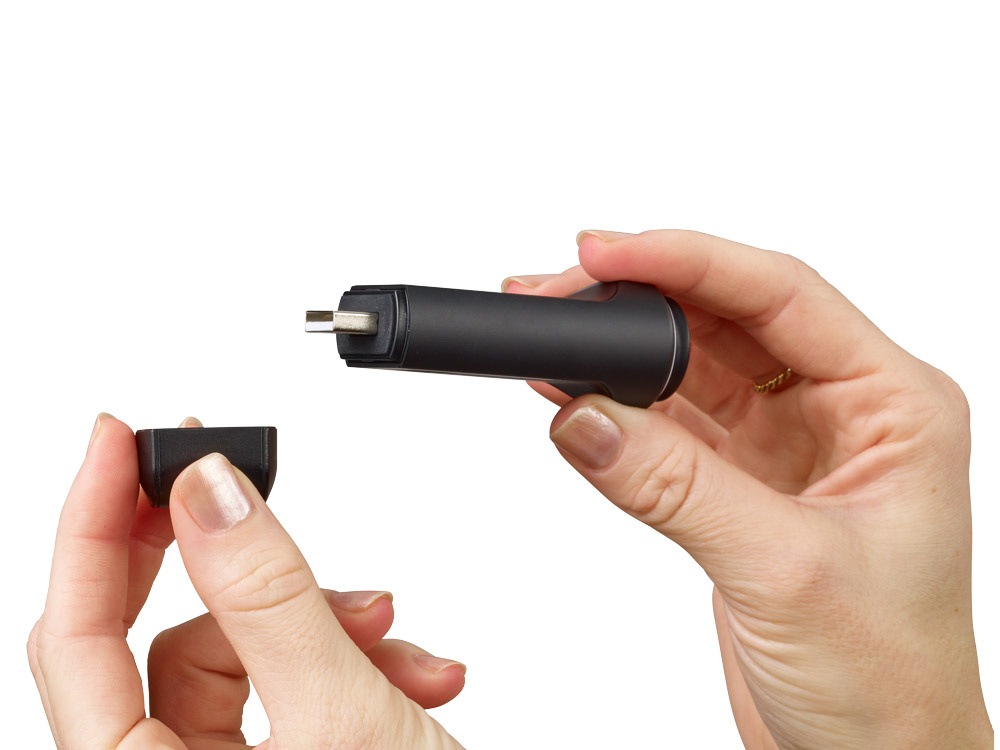 En person håller en svart navigeringssticka med en avtagbar del.