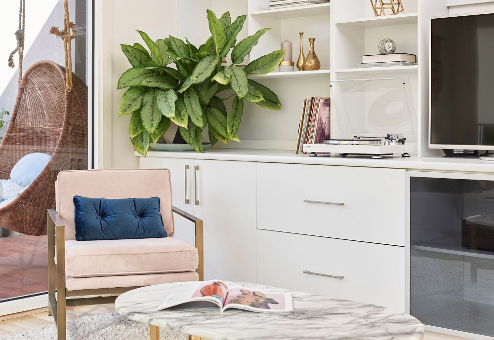 Ett modernt rum med en vinylspelare, stol och stor växt vid ett bord.