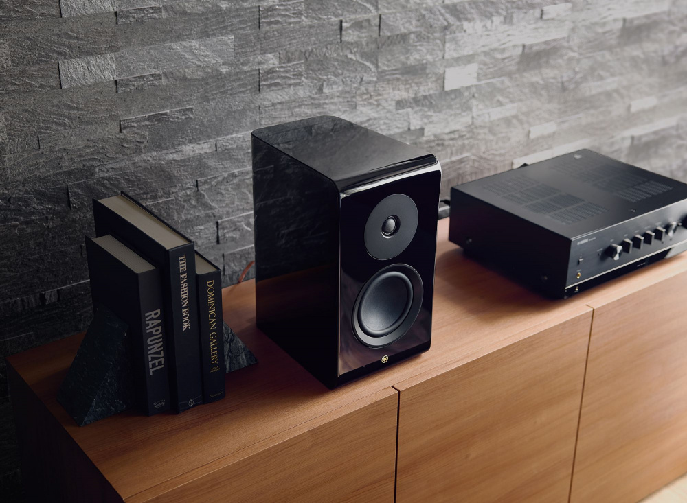 En stereoförstärkare och högtalare på en träbänk med böcker bredvid.