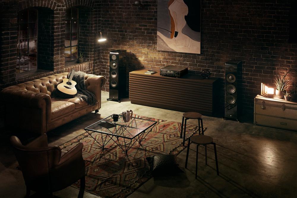 En stilren inomhusmiljö med en soffa, högtalare och en stereoförstärkare.