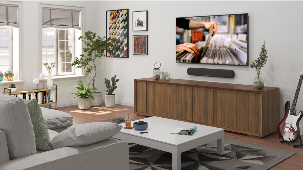 Ett elegant vardagsrum med en TV, sofa, soundbar och växter.