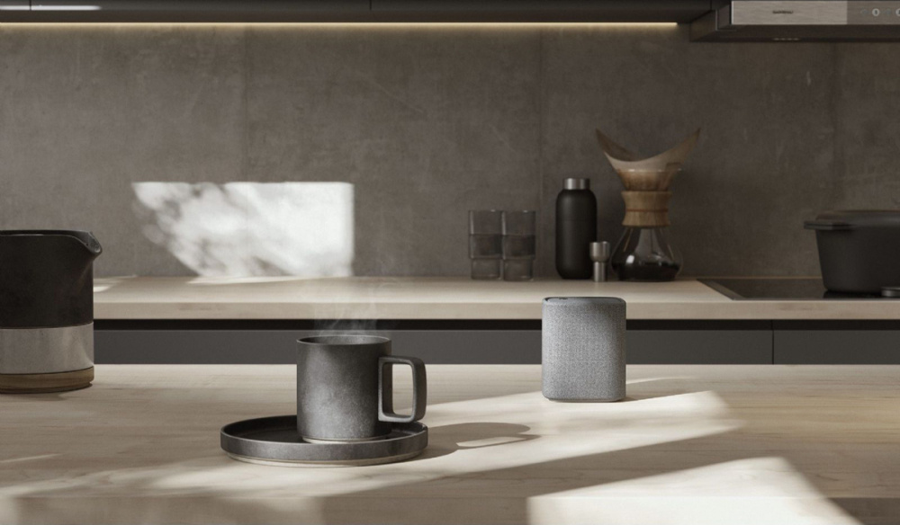 Kök med modern inredning, inkluderar kaffekopp och högtalare.