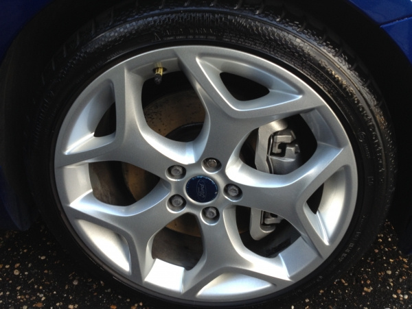 En lättrengjord fälg med ett glansigt däck, troligtvis efter användning av däckgel.