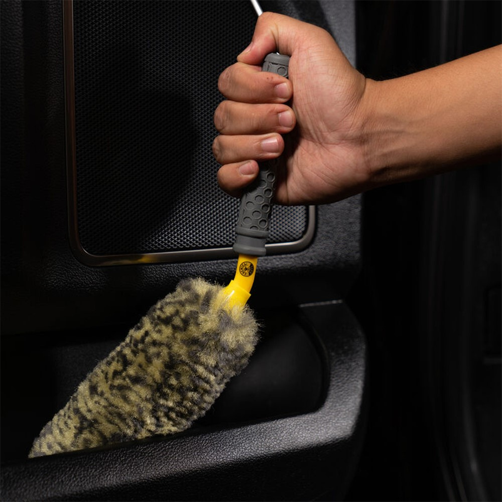 En hand håller i en borste med mjuka borst för rengöring av hjul.