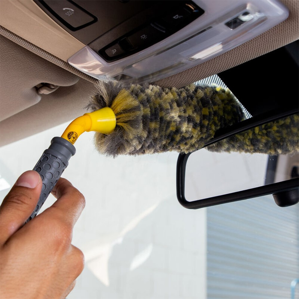 En hand som använder en hjulborste för att rengöra en bil.