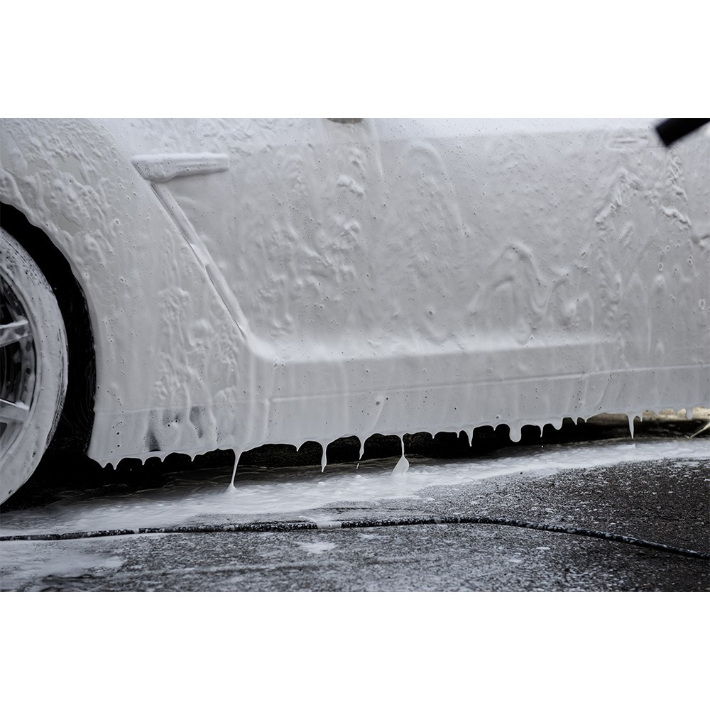 Ett bilsida täckt av skummande tvål som rinner ner på marken.