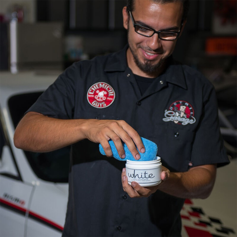 En man håller en burk med bilvård och en microfiber applikator.