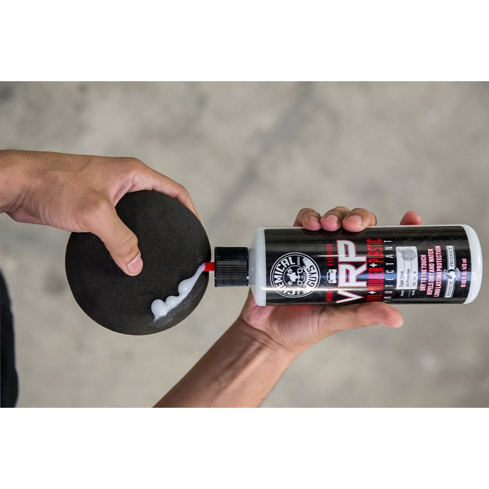 En hand häller en vit kräm från en flaska på en svart svamp.