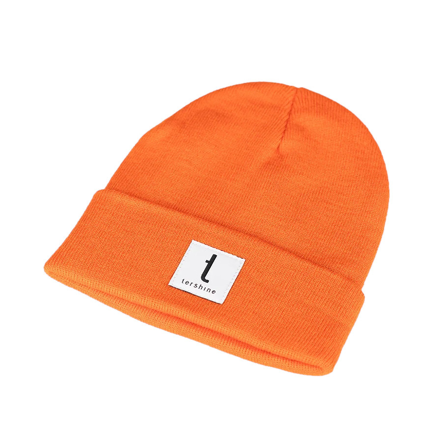 En orange beanie mössa med ett vitt märke.