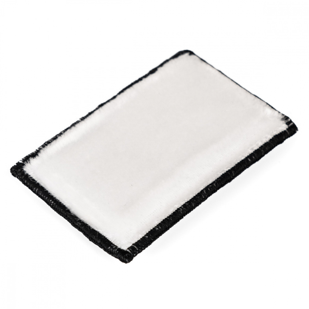 En vit rengöringssvamp med svarta kanter.