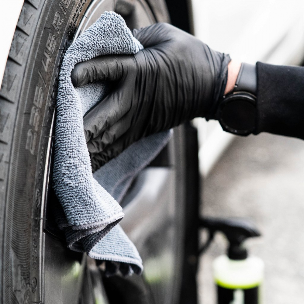 En hand kring en mikrofiberduk som torkar ett bilhjul.