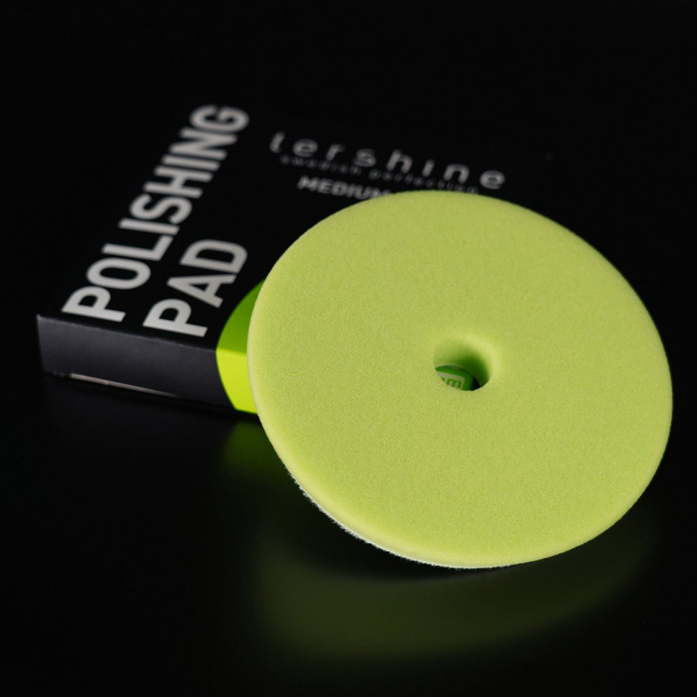 En grön polertrissa på en svart bakgrund med förpackning.