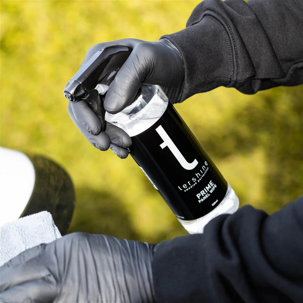 En hand håller en sprayflaska av Tershine Prime Panel Wipe.