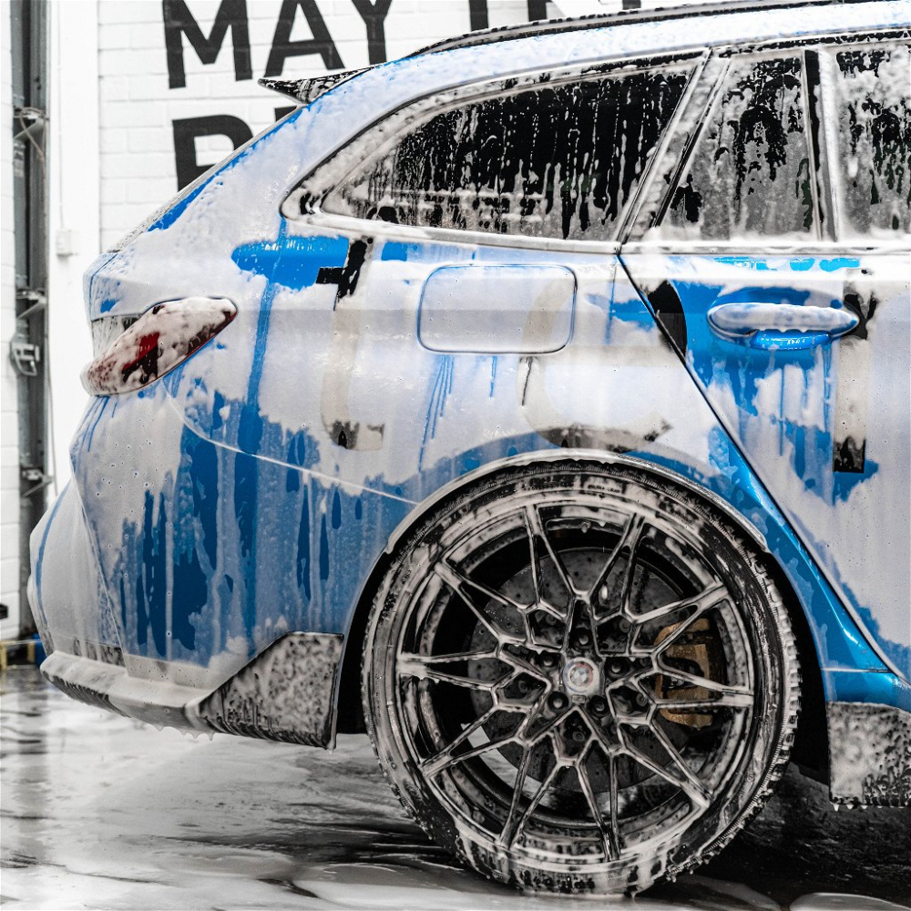 En bil täckt av schampo och skum, med fokus på bakaxeln och fälgarna.