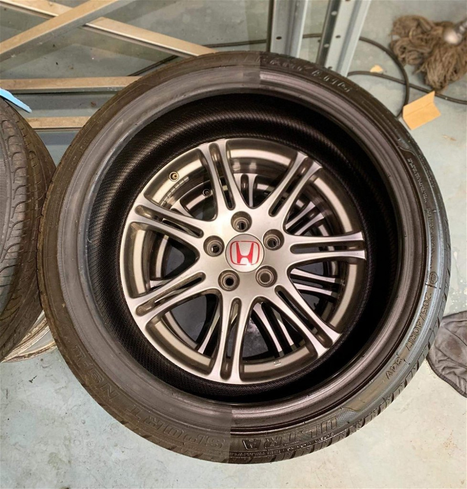 En fälg med däck och Honda-logotyp, i en verkstadsmiljö.