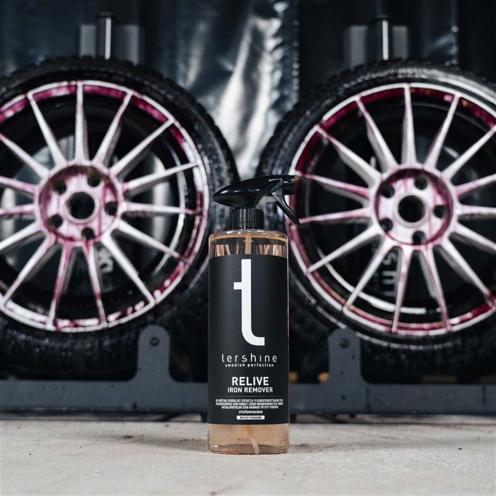 Flaska med produkter för att ta bort flygrost, med fälgar bakom.