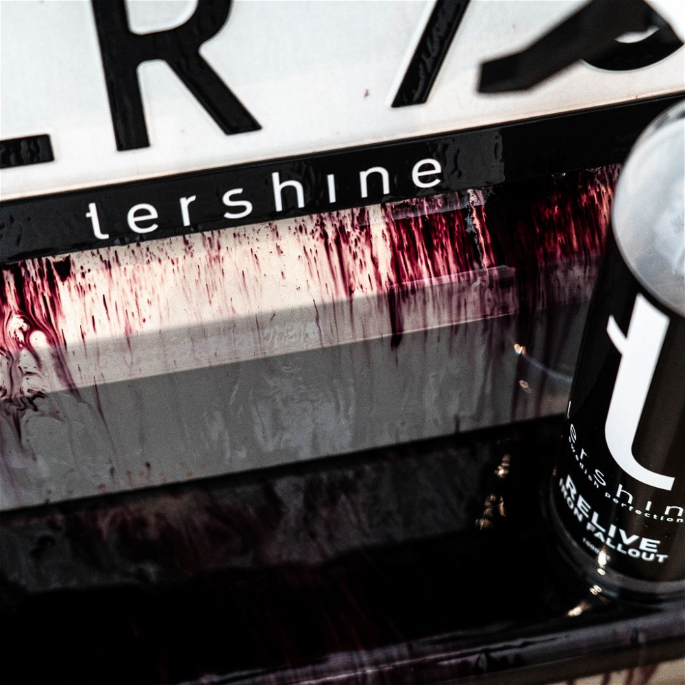 Flaska med rustborttagare och droppar av röd vätska på en yta.