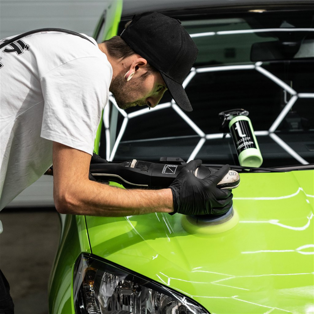 En person polerar en grön bil med en polermaskin. Tershine Restore syns i bakgrunden.