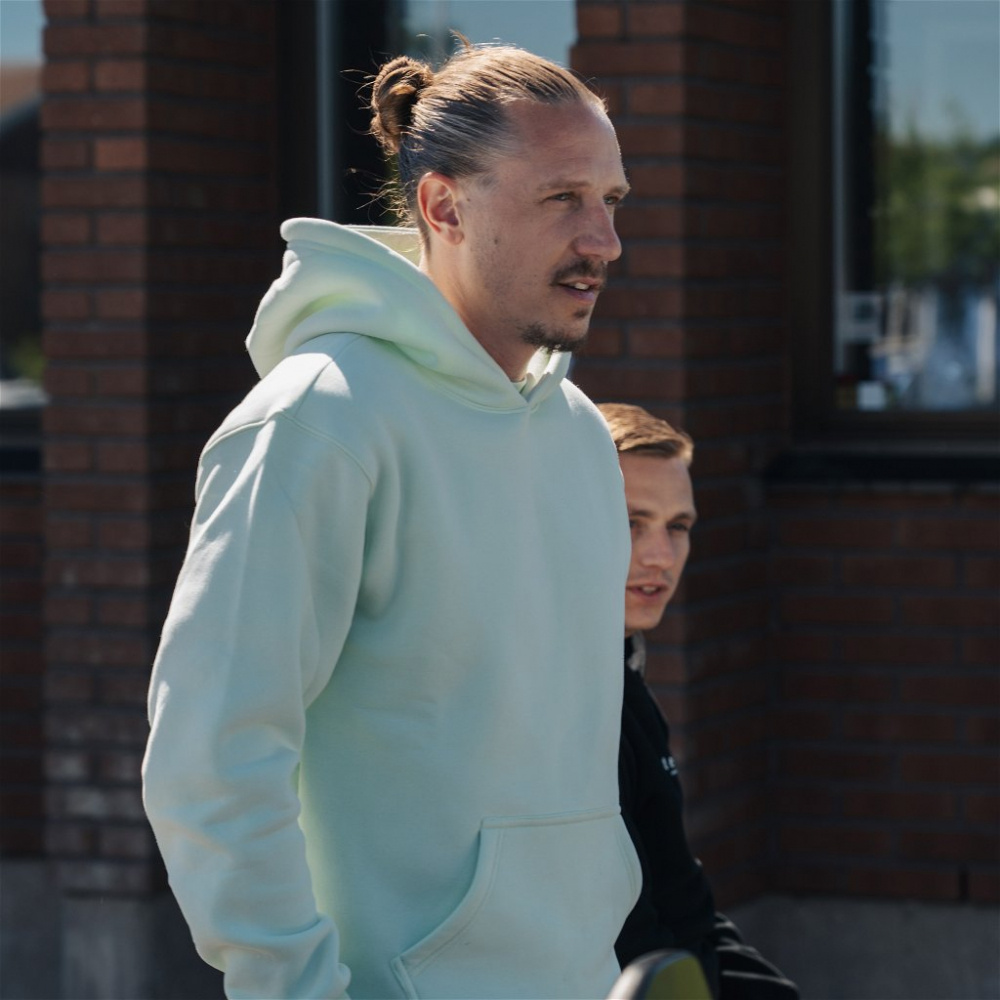 En person bär en mintgrön hoodie utomhus.