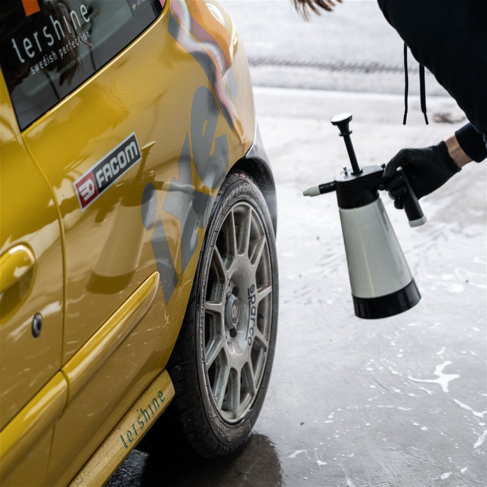 En person använder en tryckspruta för att rengöra en bils hjul.