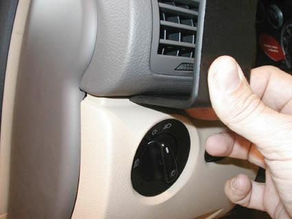 En hand håller en del av instrumentpanelen nära en rattkontroll.