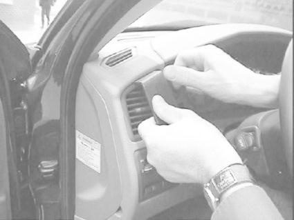 En person arbetar med en del av bilens interiör, troligtvis en luftventil.