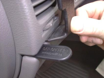 En hand som håller i en bilnyckel eller öppnare vid en bilkontrollpanel.