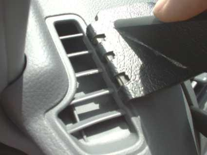 En hand som lyfter en del av ventilationsgallret i en Toyota Previa.