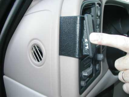 En hand som pekar på en del av bilens inredning, nära ventilen.