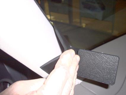 En svart plastdel monterad på bilens inre panel vid vindrutan.