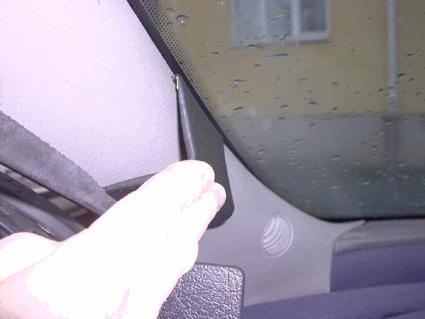 En hand håller i en del av inredningen vid bilens vindruta.