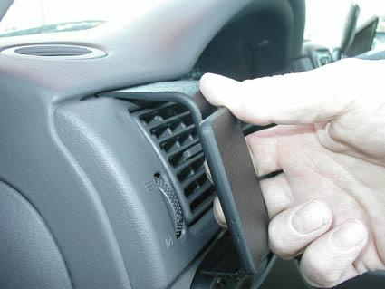 En hand tar bort en del av instrumentbrädan i en Ford Explorer.