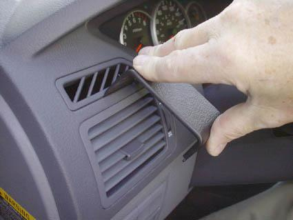 Hand som justerar luftventil i bilens frontpanel.