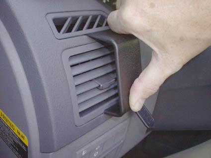En hand justerar luftutloppet i en Kia Carens 03-06.