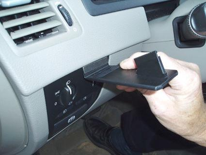 Hand tar ut en del från instrumentpanelen i en Volvo XC90 02-14.