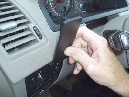 Hand som håller en svart modul inuti en bils instrumentpanel.