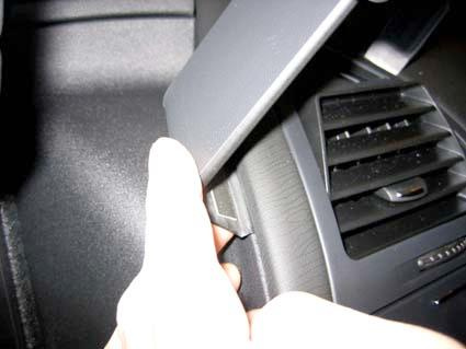 Hand som pekar på en del av bilens interiör, möjligtvis en kontrollpanel.