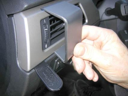 En hand håller i en del av en bils ventilationssystem.