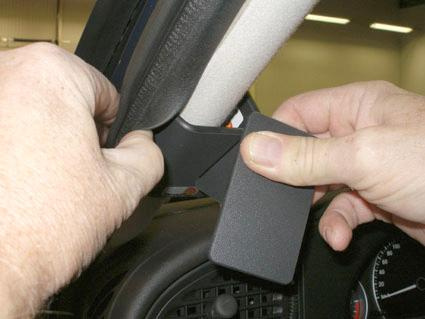 En person fäster en del på bilens inredning, Saab 9-5 06-10, vänster sida.